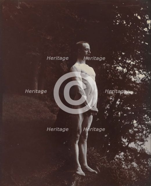 A man posing naked, standing with his chest out, arms down and hands clasped, approx 1900. Creator: Unknown.