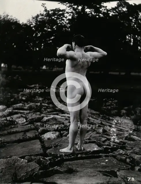 A man posing naked, with his back to the camera, standing on a rocky outcrop, c1900. Creator: Unknown.