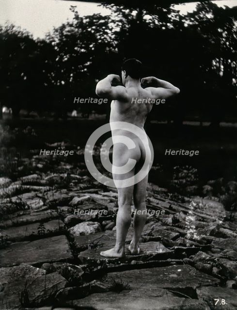 A man posing naked, with his back to the camera, standing on a rocky outcrop, c1900. Creator: Unknown.