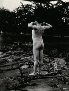 A man posing naked, with his back to the camera, standing on a rocky outcrop, c1900. Creator: Unknown