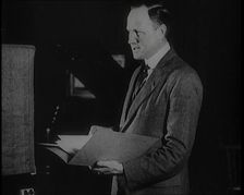 A Man Reading from a Book for the British Broadcasting Corporation, 1922. Creator: British Pathe Ltd