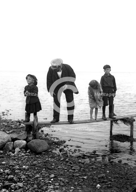 A man with three children on a jetty, Landskrona, Sweden, 1910. Creator: Unknown.