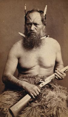A Maori man with a tattoed face, holding a rifle, c1870s. Creator: James Bragge
