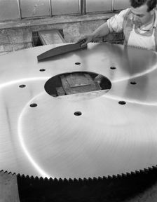 A machinist quality checking a six foot circular saw blade, Sheffield, South Yorkshire, 1963. Creator: Michael Walters