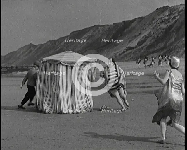 A Male Actor With a Moustache and Bowler Hat Being Chased Around a Changing Tent On a Beach...,1920s Creator: British Pathe Ltd.