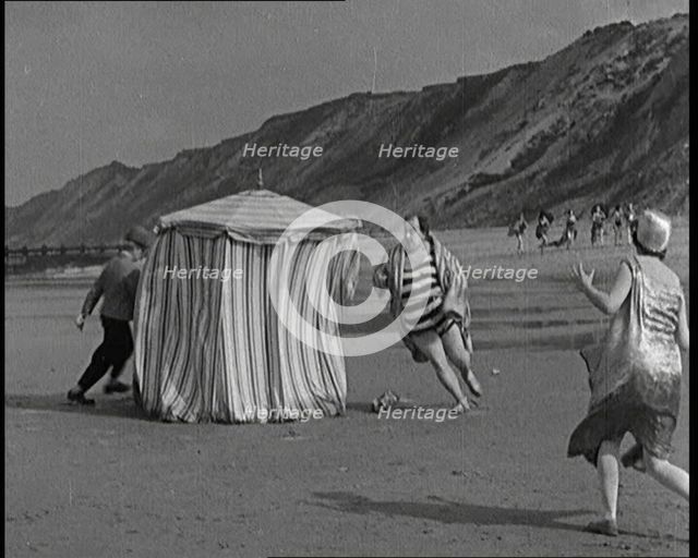 A Male Actor With a Moustache and Bowler Hat Being Chased Around a Changing Tent On a Beach...,1920s Creator: British Pathe Ltd.
