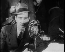 A Male American Civilian in a Press Room Speaking at a Microphone That Has the Words NBC..., 1930s. Creator: British Pathe Ltd