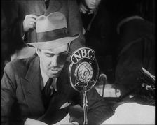 A Male American Civilian in a Press Room Speaking at a Microphone That Has the Words NBC..., 1930s. Creator: British Pathe Ltd