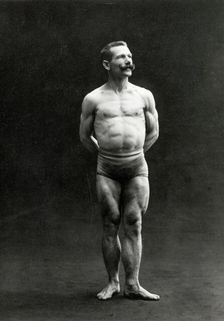 A male bodybuilder wearing bathing trunks, posing in a studio setting, between 1899 and 1908. Creator: Unknown