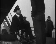 A Male Customs Official Standing by a Hatch and Talking to a Man on Board a Large Ship in..., 1939. Creator: British Pathe Ltd
