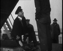 A Male Customs Official Standing by a Hatch and Talking to a Man on Board a Large Ship in..., 1939. Creator: British Pathe Ltd