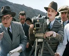A Male Cameraman Cranking a Camera On a Film Set as the Male Director Instructs Actors, 1920s. Creator: British Pathe Ltd