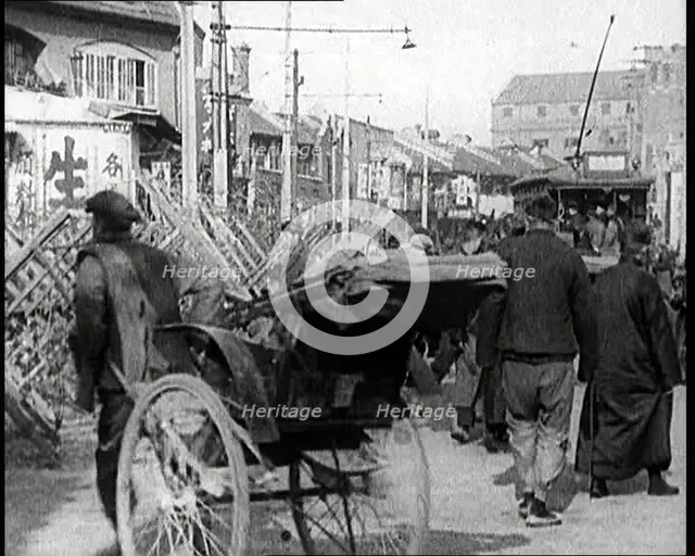 A Male Chinese Civilian Pulling Rickshaws Through the Streets of Shanghai Past Barricades, 1920s. Creator: British Pathe Ltd.