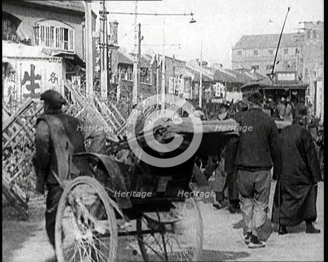 A Male Chinese Civilian Pulling Rickshaws Through the Streets of Shanghai Past Barricades, 1920s. Creator: British Pathe Ltd.