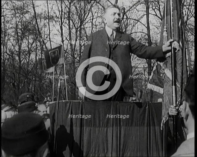 A Male Civilian Makes a Speech from a Stand in Front of a Crowd of Male Civilians Carrying..., 1924. Creator: British Pathe Ltd.