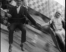 A Male Civilian and a Female Civilian Holding Hands as They Are Spun Through the Air on a..., 1924. Creator: British Pathe Ltd