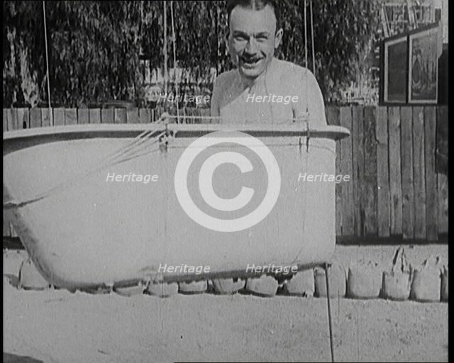 A Male Civilian Sitting in a Bath Before the Bath is Lifted Off the Ground By a Hot Air..., 1920s. Creator: British Pathe Ltd.