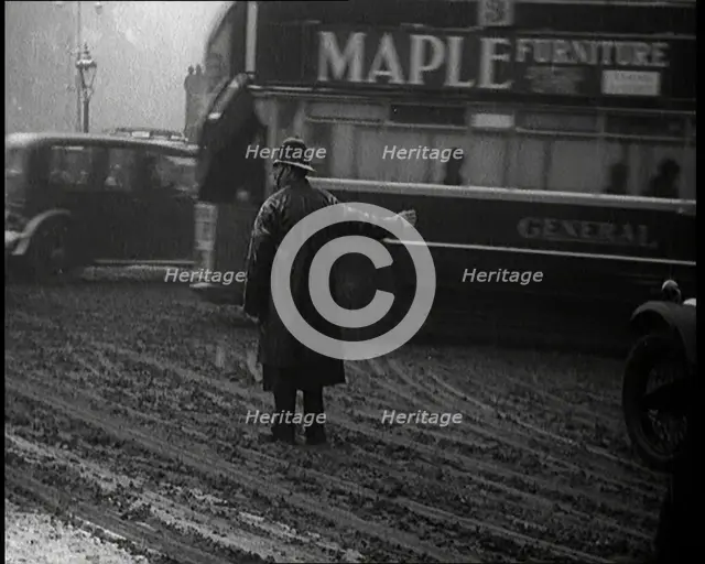 A Male Police Officer Directing the Traffic in the Snow, With His Back to the Camera, 1920s. Creator: British Pathe Ltd.