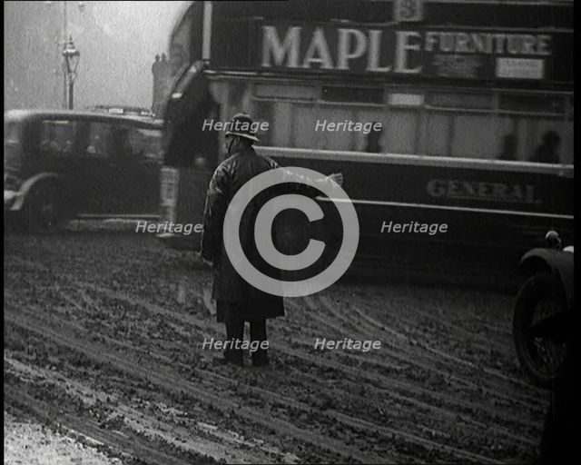 A Male Police Officer Directing the Traffic in the Snow, With His Back to the Camera, 1920s. Creator: British Pathe Ltd.