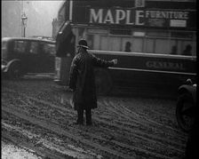 A Male Police Officer Directing the Traffic in the Snow, With His Back to the Camera, 1920s. Creator: British Pathe Ltd