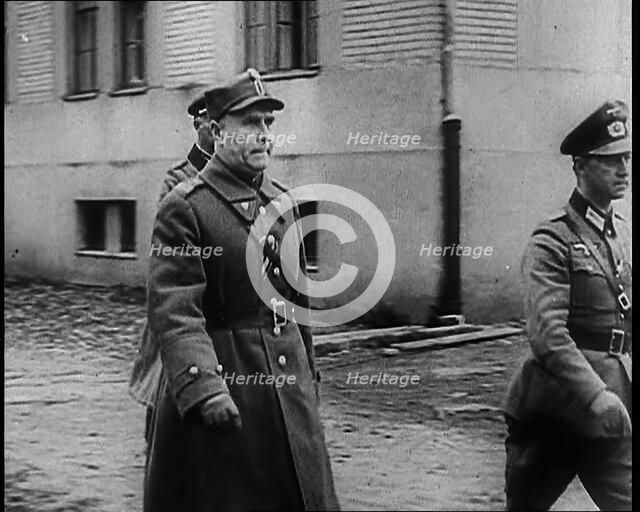 A Male Polish Army Commander Walking Past the Corner of a Large Building With Two Male... 1939. Creator: British Pathe Ltd.