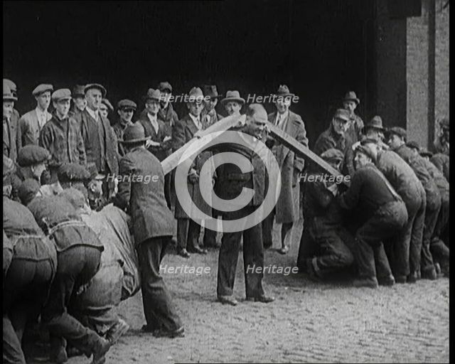 A Male Stuntman Bending Girders Over His Shoulders, 1926. Creator: British Pathe Ltd.