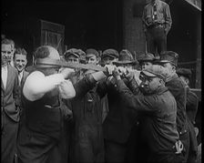 A Male Stuntman Bending Iron Bars Around His Head, 1926. Creator: British Pathe Ltd