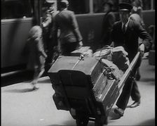 A Male Train Station Porter Pushing a Sack Barrow With Suitcases and Bags on it Along..., 1938. Creator: British Pathe Ltd