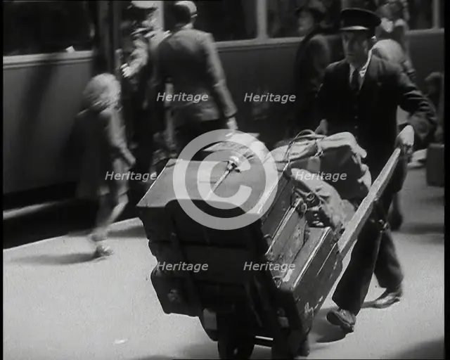 A Male Train Station Porter Pushing a Sack Barrow With Suitcases and Bags on it Along..., 1938. Creator: British Pathe Ltd.