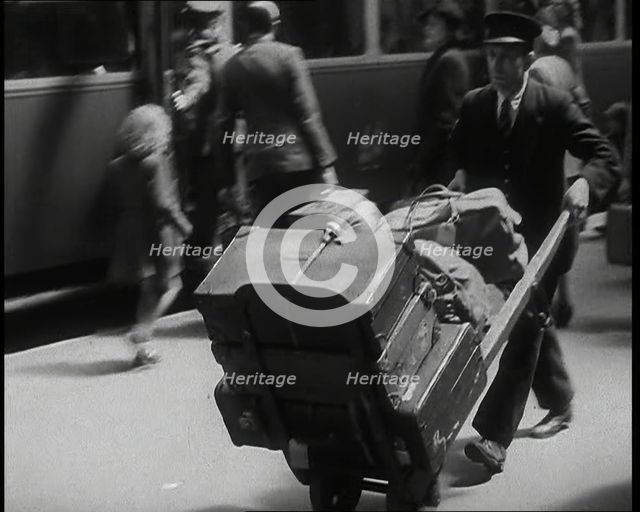 A Male Train Station Porter Pushing a Sack Barrow With Suitcases and Bags on it Along..., 1938. Creator: British Pathe Ltd.