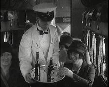 A Male Waiter Serves Smiling and Laughing Passengers Drinks Inside an Aircraft, 1920s. Creator: British Pathe Ltd