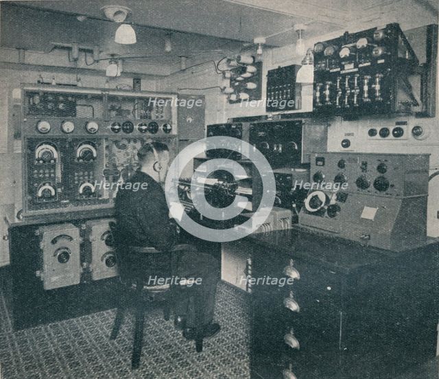 'A Marconi wireless operator receiving wireless messages as the Empress of Britain crosses the Atlan Artist: Unknown.