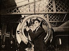 A metal worker with automatic drill stripping an engine casing, 1940