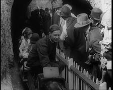 A Model Train Passes Through a Tunnel As a Crowd of People Watch from Behind a Fence, 1924. Creator: British Pathe Ltd