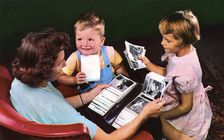 A mother and children looking at photos in a family album, Blackwood, New Jersey, USA, 1956