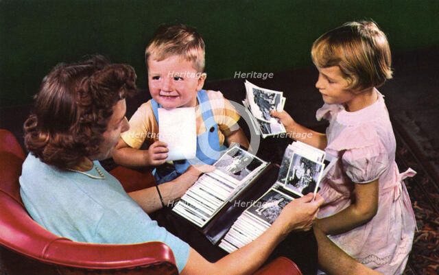 A mother and children looking at photos in a family album, Blackwood, New Jersey, USA, 1956. Artist: Unknown