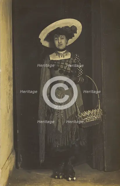 A person wearing a dress, large hat and roller skates, poses holding a basket, (1910-1919?). Creator: Unknown.