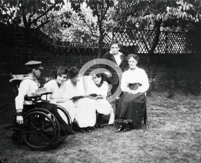 A physically disabled boy sitting in a wheelchair in a garden,  c1910/1925. Creator: Unknown.