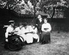 A physically disabled boy sitting in a wheelchair in a garden, c1910/1925. Creator: Unknown