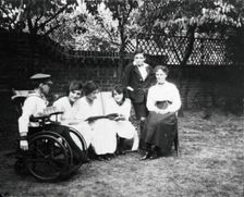 A physically disabled boy sitting in a wheelchair in a garden, c1910/1925. Creator: Unknown