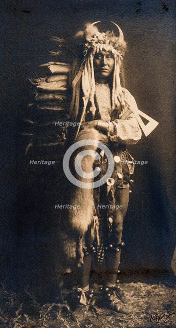 A Piegan man, Iron Breast, in ceremonial dress, 1900. Creator: Edward Sheriff Curtis.
