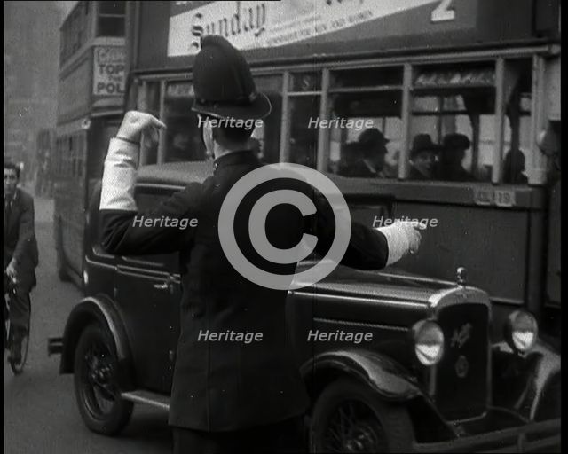 A Police Officer Guiding Traffic on the Streets of London, 1936. Creator: British Pathe Ltd.