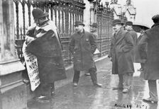 A policeman removes a suffragette poster from the railings, House of Commons, London, March 1909. Creator: Unknown