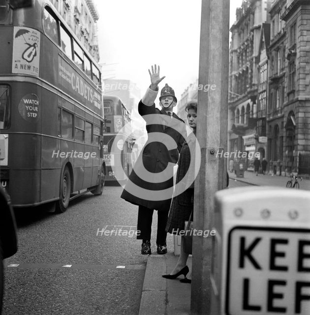 A policeman with his arm raised as two double decker buses pass by, City of London c1946-c1959. Artist: John Gay