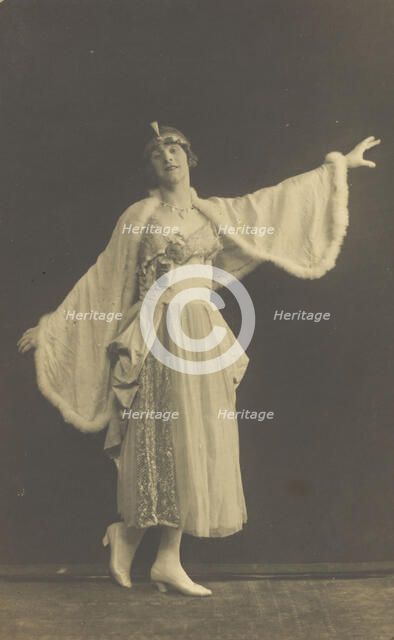 A prisoner of war in drag, wearing a dress and white cloak, poses...(between 1910 and 1919?). Creator: Albert Melzer.