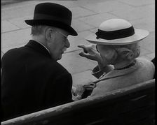 A Rear View of a Elderly Man and Woman Sitting on a Bench and Talking, Both Wearing Hats..., 1938. Creator: British Pathe Ltd