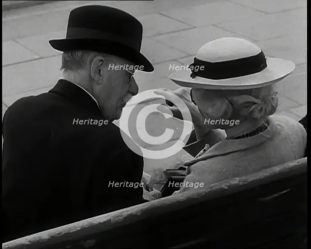 A Rear View of a Elderly Man and Woman Sitting on a Bench and Talking, Both Wearing Hats..., 1938. Creator: British Pathe Ltd.