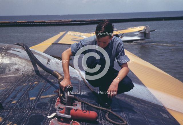 A sailor mechanic refueling a plane at the Naval Air Base, Corpus Christi, Texas, 1942. Creator: Howard Hollem.