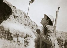 A sentry in the trenches looking through an improvised persicope, France, World War I, 1916