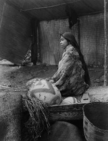 A Skokomish Indian chief's daughter, half-length portrait, seated on canoe, facing left, c1913. Creator: Edward Sheriff Curtis